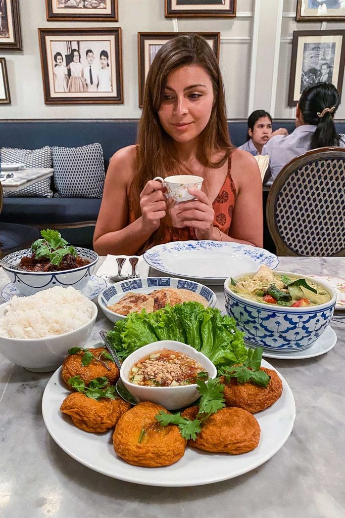 Melissa sitting at a table with dishes of traditional thai food