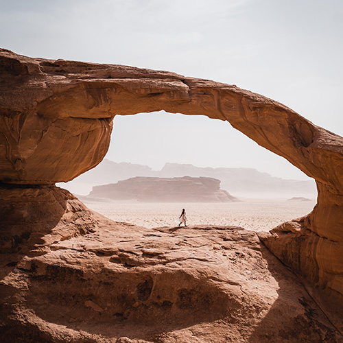 Melissa stands in the centre of a grand rock bridge in the Wadi Rum desert.