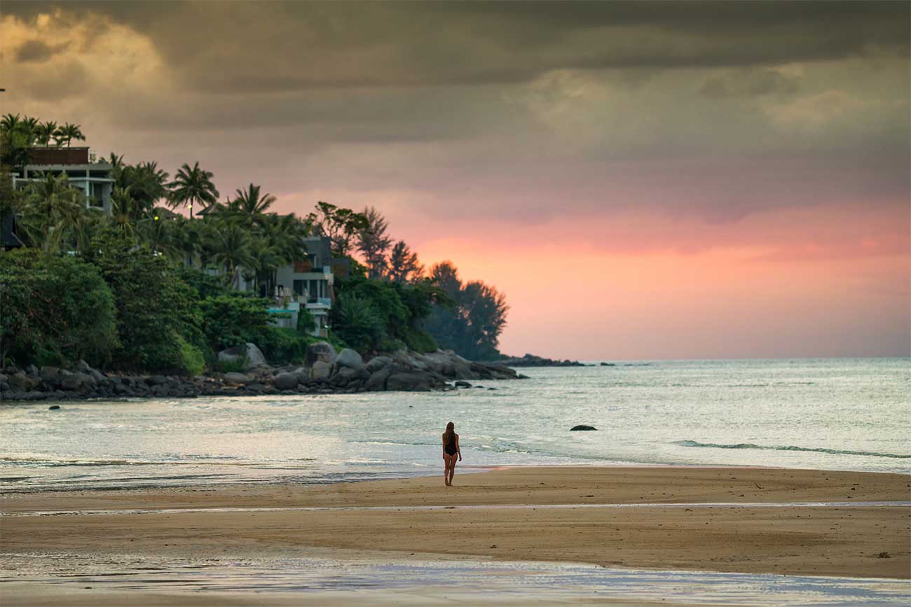 Person walking towards the ocean at sunset at Kamala Beach