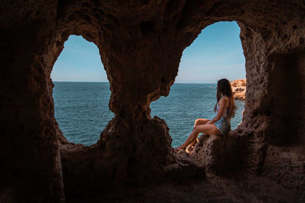 Melissa sitting on a rock cave in Algar Seco in Lagos Portugal
