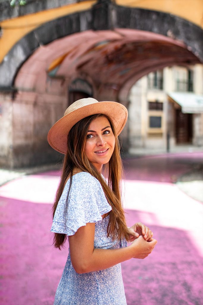 Melissa looks over her shoulder and smiles on the pink street of Lisbon.