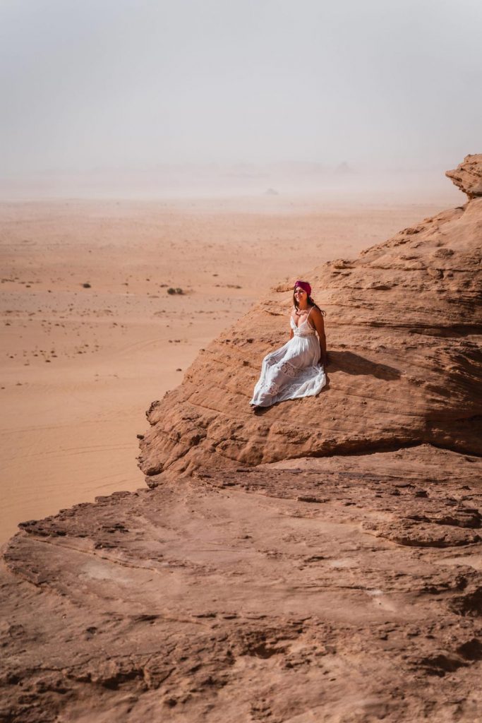 Melissa sides on a rock formation, overlooking the vast Wadi Rum desert.