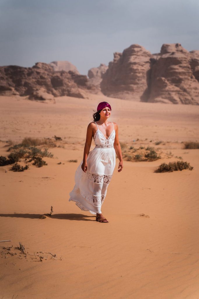 Melissa standing in a long white dress in the middle of the Wadi Rum desert.