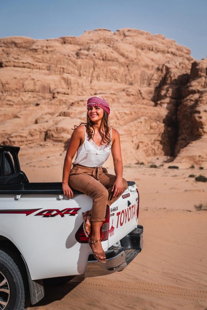 Melissa sits on the back of a Jeep in the Wadi Rum desert.