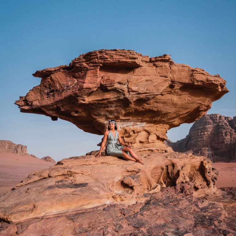 Melissa sits beside mushroom rock, a cool rock formation in the Wadi Rum desert.