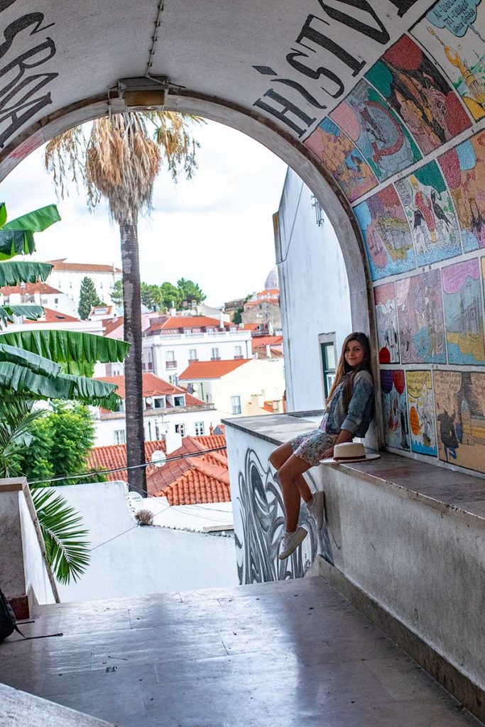 Melissa sits in a tunnel filled with street art in the Alfama District of Lisbon