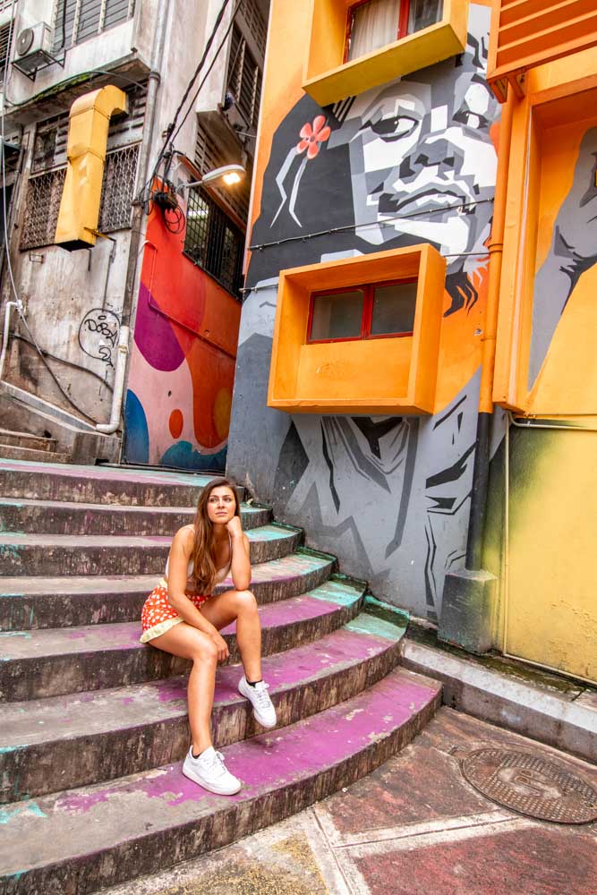 Melissa sits on the stairs of the colourful graffiti streets of Bukit Bintang in KL.
