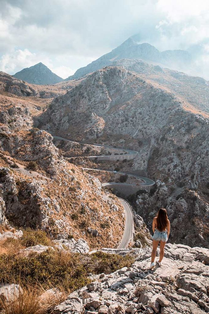 Melissa standing on a rock with the winding roads of Sa Calobra in the background